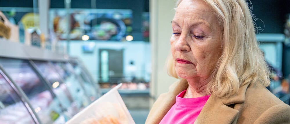 Eine Frau betrachtet in einem Supermarkt Tiefkühlfleisch (Symbolbild).