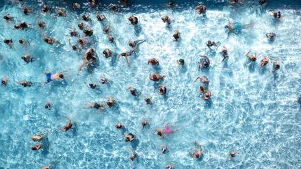 Zahlreiche Badegäste sind in einem Freibad zu sehen.