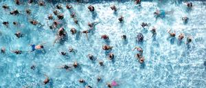 Zahlreiche Badegäste sind in einem Freibad zu sehen.