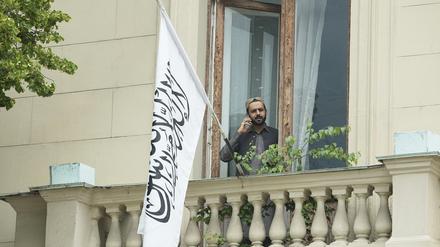 Ein Mann telefoniert auf einem Balkon der afghanischen Botschaft in Moskau vor der Flagge des Islamischen Emirats Afghanistan.