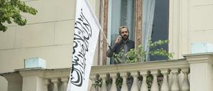 Ein Mann telefoniert auf einem Balkon der afghanischen Botschaft in Moskau vor der Flagge des Islamischen Emirats Afghanistan.