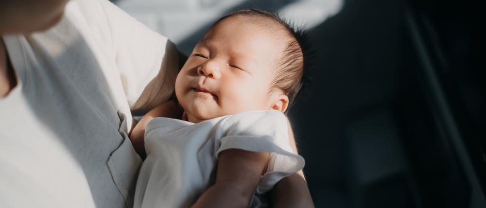 Ein asiatisches Baby schläft im Arm seiner Mutter. Nicht überall ist das Geschlecht eines Kindes dem Zufall überlassen.