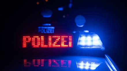Zwei Polizisten stehen vor einem Polizeifahrzeug (gestellte Szene).