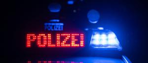 Zwei Polizisten stehen vor einem Polizeifahrzeug (gestellte Szene).