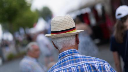 02.07.2025, Nordrhein-Westfalen, Aachen: Ein älterer Mann trägt einen Strohut mit einer Banderole in Deutschlandfarben.