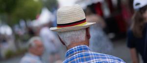 02.07.2025, Nordrhein-Westfalen, Aachen: Ein älterer Mann trägt einen Strohut mit einer Banderole in Deutschlandfarben.