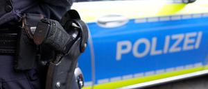 Ein Polizist steht vor einem Einsatzfahrzeug der Polizei (Symbolbild).