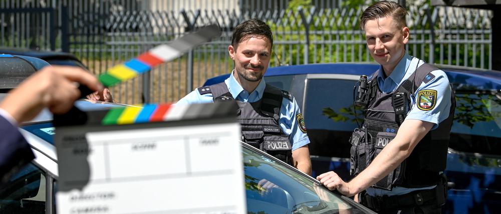 Drehen Kurz-Videos mit Botschaften: Polizeihauptkommissar Sebastian Schultzik (l) und Polizeimeister Arthur Gamm stehen an einem Polizeifahrzeug in der Polizeiinspektion in Halle.