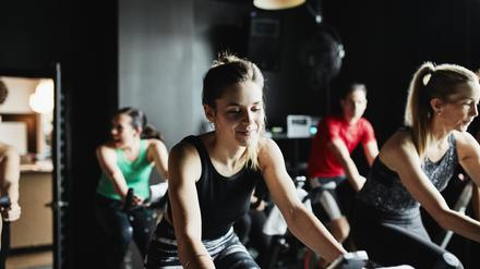 Eine Fitnessklasse auf stehenden Fahrrädern im Studio..