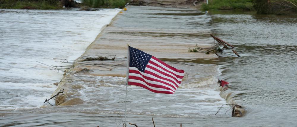 Eine US-Flagge weht am Ufer des Guadalupe-Flusses, der zu einer tödlichen Flut angeschwollen ist.