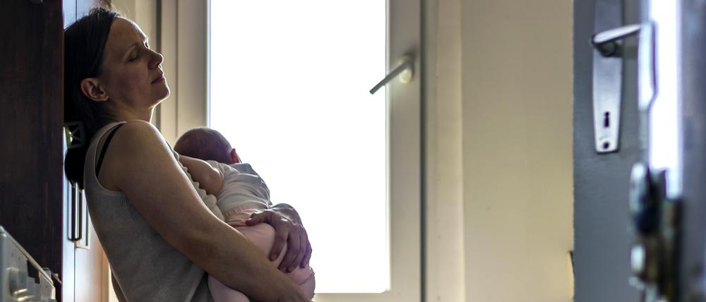 Eine erschöpfte Mutter hält verängstigt ihr neugeborenes Baby im Arm. (Symbolbild)