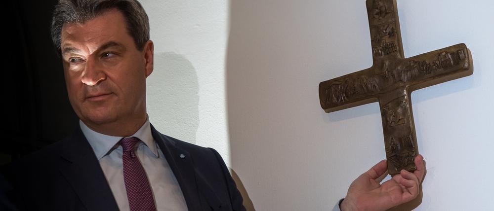 Markus Söder, Bayerischer Ministerpräsident (CSU), hängt ein Kreuz im Eingangsbereich der bayerischen Staatskanzlei auf. 