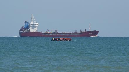 Mutmaßliche Migranten an Bord eines RIB (festes aufblasbares Boot) fahren im Ärmelkanal vor der Küste von Calais an einem Schiff vorbei.