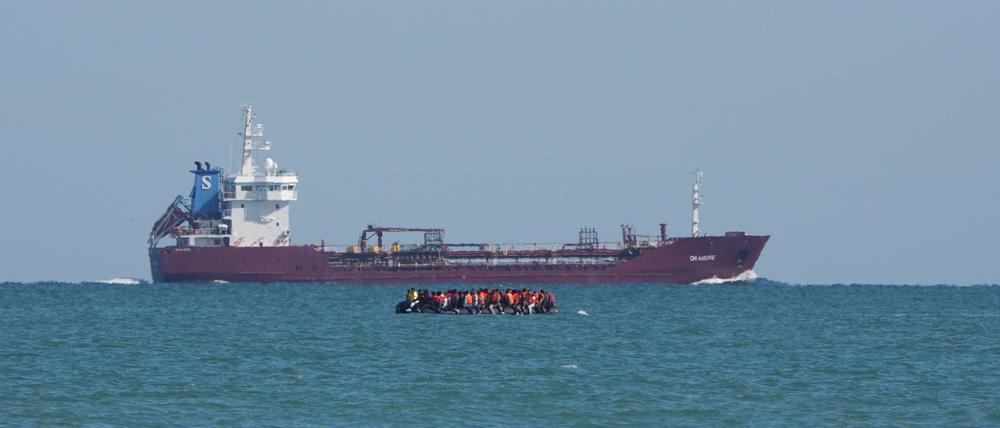 Mutmaßliche Migranten an Bord eines RIB (festes aufblasbares Boot) fahren im Ärmelkanal vor der Küste von Calais an einem Schiff vorbei.