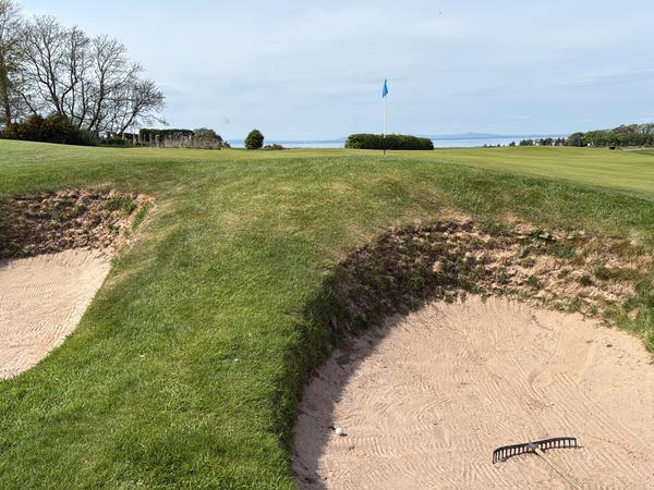 Golfgrün mit Bunkern davor. Ein Ball liegt links in einem der Bunker.