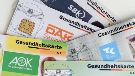 Gesundheitskarten verschiedener Krankenkassen liegen auf einem Tisch.