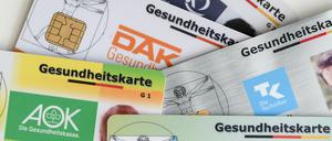 Gesundheitskarten verschiedener Krankenkassen liegen auf einem Tisch.