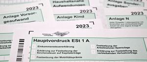 Formulare für die Einkommenssteuererklärung mit Anlagen liegen auf einem Schreibtisch. 