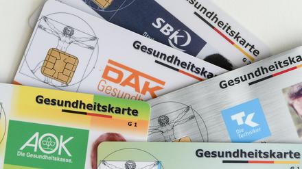 Gesundheitskarten verschiedener Krankenkassen liegen auf einem Tisch.