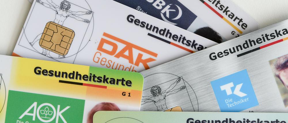 Gesundheitskarten verschiedener Krankenkassen liegen auf einem Tisch.