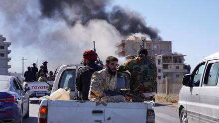 Rauch steigt auf, während syrische Sicherheitskräfte auf dem Rücksitz eines Lastwagens sitzen.