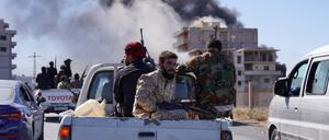 Rauch steigt auf, während syrische Sicherheitskräfte auf dem Rücksitz eines Lastwagens sitzen.