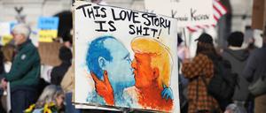 Ein Demonstrant hält ein Plakat, auf dem Donald Trump und Wladimir Putin abgebildet sind, die sich während einer Anti-Trump-Demonstration vor dem Pennsylvania State Capitol küssen.