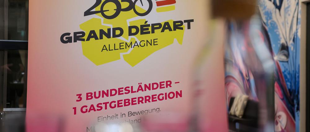 Das Logo für die Bewerbung zum geplanten Start der Tour de France 2030 in Ostdeutschland hängt auf einer Pressekonferenz.
