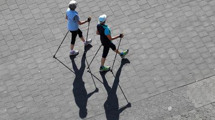Zwei ältere Damen gehen mit Walking-Stöcken spazieren. 