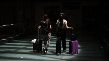 Zwei Reisende schieben ihre Koffer.