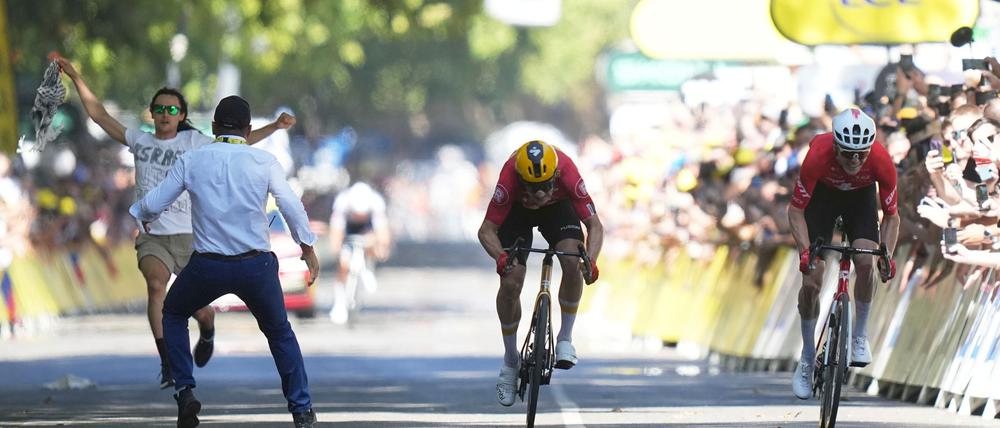 Ein Sicherheitsbeamter drängt in Toulouse einen Flitzer von der Zielgeraden, während Jonas Abrahamsen und Mauro Schmid um den Sieg sprinten.