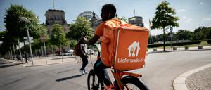 Ein Fahrradkurier des Essens-Lieferdienstes Lieferando fährt mit seinem Rucksack am Reichstagsgebäude in Berlin vorbei.