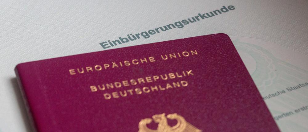 Eine Einbürgerungsurkunde der Bundesrepublik Deutschland und ein deutscher Reisepass liegen auf einem Tisch. (Symbolbild)