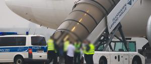 Menschen besteigen ein Flugzeug der Qatar Airways, vor dem Fahrzeuge der Bundespolizei stehen auf dem Vorfeld am Flughafen Leipzig/Halle.