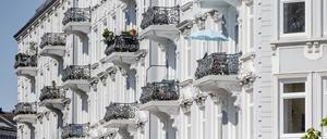 Fassade eines Altbau-Mehrfamilienhauses mit vielen Balkons, auf einem steht ein Sonnenschirm.