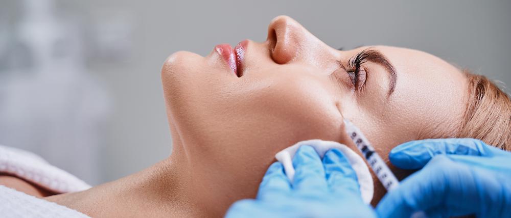 Eine Frau erhält eine Hyaluroninjektion im Gesicht.