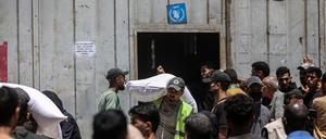 12.07.2025, Palästinensische Gebiete, Gaza: Palästinenser tragen Säcke mit Mehl weg, während andere vor einer vom Welternährungsprogramm der Vereinten Nationen (WFP) eingerichteten Verteilerstelle in Gaza-Stadt warten.