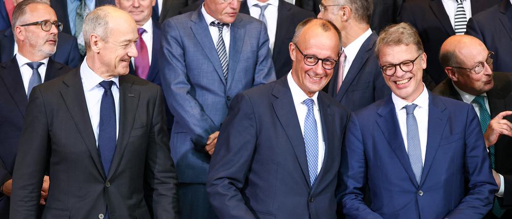 Bundeskanzler Friedrich Merz (Mitte) mit den CEOs von Siemens und Deutscher Bank, Roland Busch (links) und Christian Sewing (rechts).