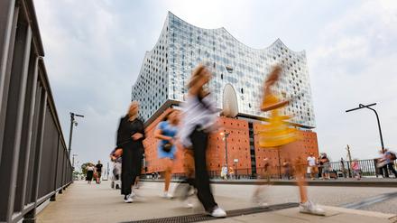Menschen gehen vor der Elbphilharmonie in Hamburg entlang (Symbolbild).