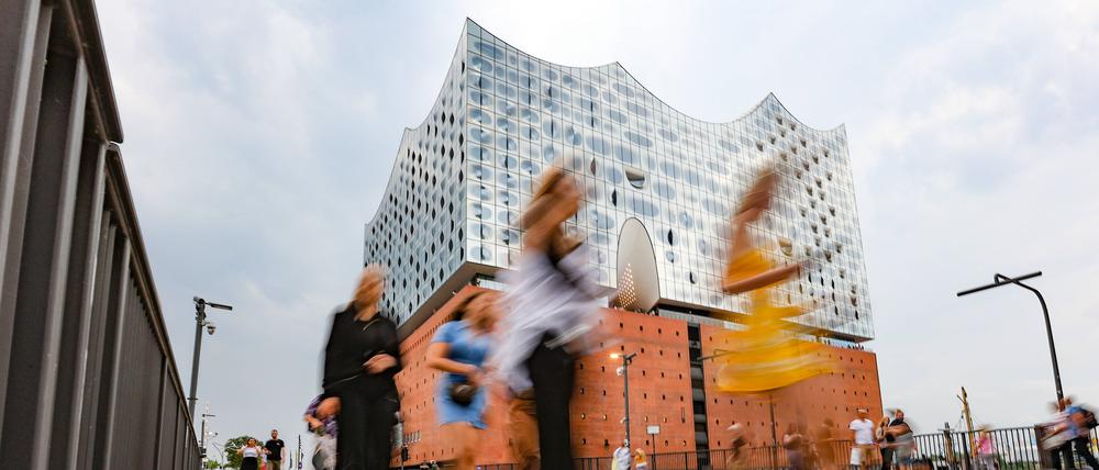 Menschen gehen vor der Elbphilharmonie in Hamburg entlang (Symbolbild).