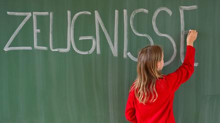 Eine Viertklässlerin schreibt in einer Grundschule das Wort „Zeugnisse“ auf eine Tafel.