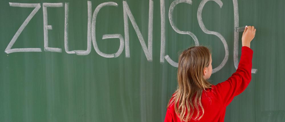 Eine Viertklässlerin schreibt in einer Grundschule das Wort „Zeugnisse“ auf eine Tafel.