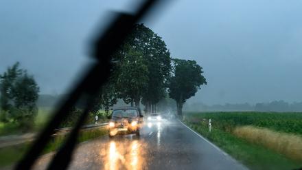 Während eines heftigen Regenschauers sind Autos auf einer Landstraße im östlichen Brandenburg unterwegs.