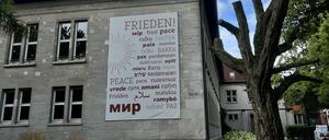 Das Wort Frieden, übersetzt in mehrere Sprachen, hängt an der Außenwand des Canisius Kollegs“.