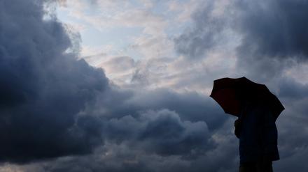 Mensch mit Schirm trotzt dem Regen – während das Tief „Isaac“ stellenweise Jahrhundertniederschläge brachte.