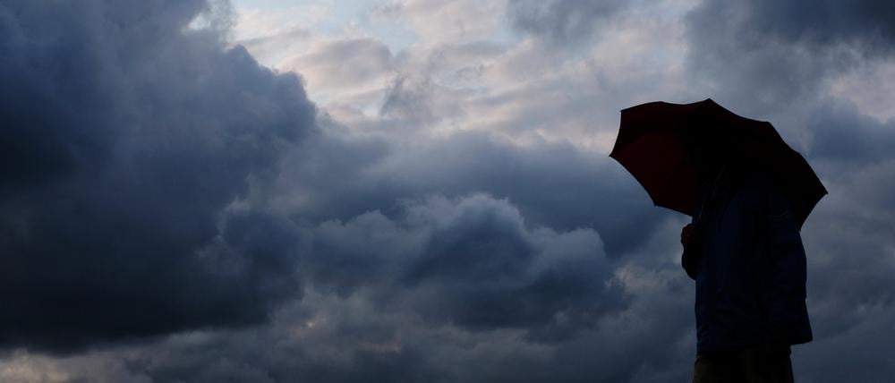 Mensch mit Schirm trotzt dem Regen – während das Tief „Isaac“ stellenweise Jahrhundertniederschläge brachte.