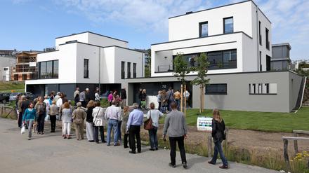 Interessenten stehen Schlange zur Besichtigung eines Neubau-Einfamilienhauses 