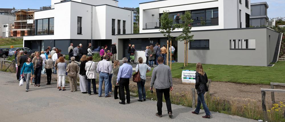Interessenten stehen Schlange zur Besichtigung eines Neubau-Einfamilienhauses 