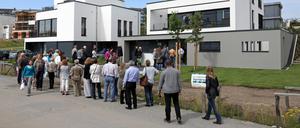 Interessenten stehen Schlange zur Besichtigung eines Neubau-Einfamilienhauses 