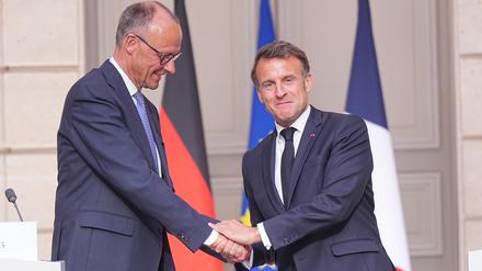 Der französische Präsident Emmanuel Macron (r) gibt Bundeskanzler Friedrich Merz (CDU) die Hand nach einer Pressekonferenz in Paris. 